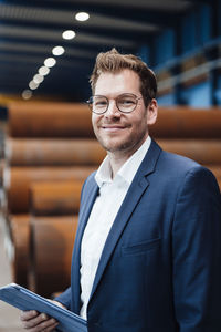 Smiling businessman with digital tablet at warehouse