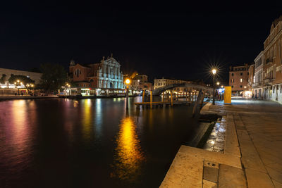 Illuminated buildings by river at night