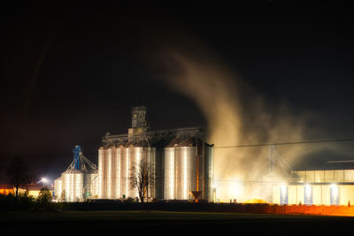 Grain dryer plant working at night with steam floating around it. the agro farm metal elevator.