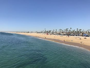 Group of people on beach against clear blue sky