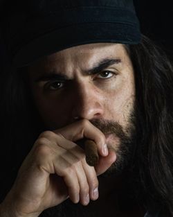 Close-up portrait of man wearing hat against black background