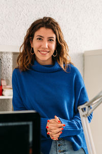 Portrait of a smiling young woman using phone at home