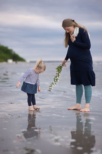 Rear view of mother and daughter walking in water