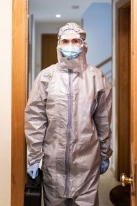 Portrait of woman in protective suit standing at home