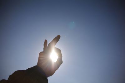 Low angle view of cropped hand against sky