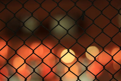 Full frame shot of chainlink fence against sky during sunset