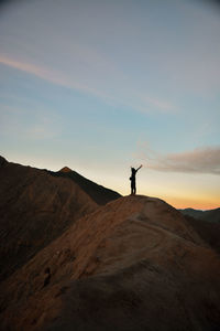 Silhouette man standing on mountain at sunset