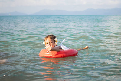 Adorable toddler toddler swim in the sea in a special inflatable life ring.