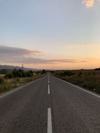 Surface level of road against sky at sunset