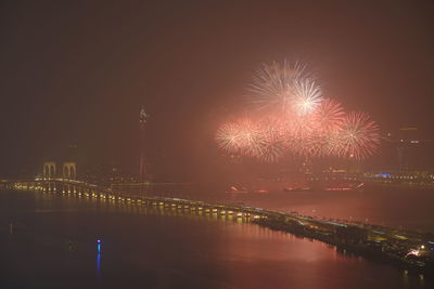 Firework display over river against sky at night