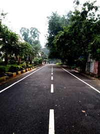 Road amidst trees and city against sky