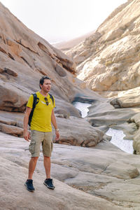Man standing in front of rocky canyon in the mountains of fuerteventura, spain