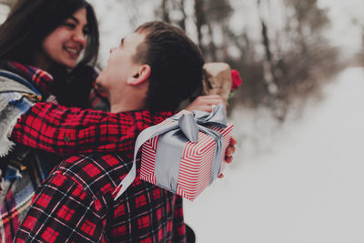 Boyfriend giving a gift box present with ribbon outdoor due to saint valentine day to her girlfriend