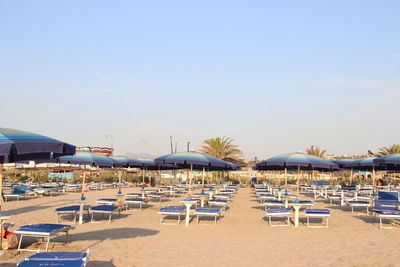 Chairs on beach by swimming pool against sky