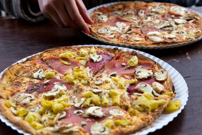 Cropped image of woman having mushroom pizza at table