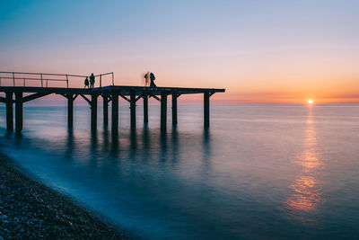 Silhouette pier over sea against sky during sunset