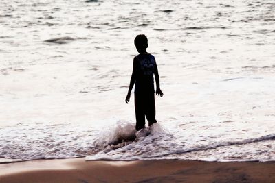 Rear view of boy standing on shore