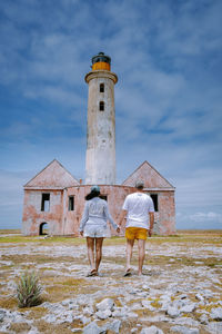 Rear view of man standing by lighthouse against sky