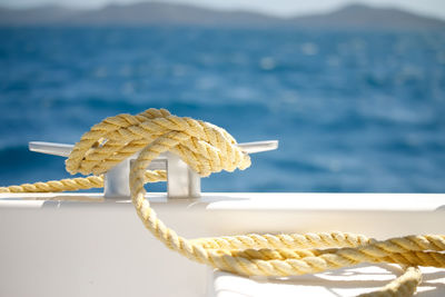 Close-up boat cleat with yellow rope water in background