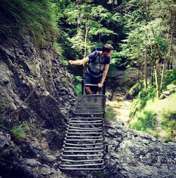 Man climbing on rock in forest