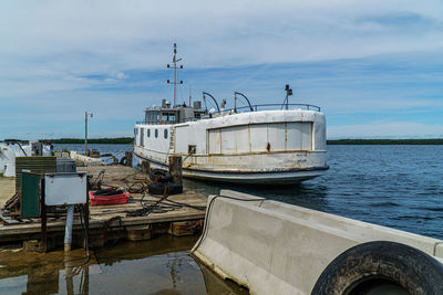 Fishing boat moored at harbor against sky