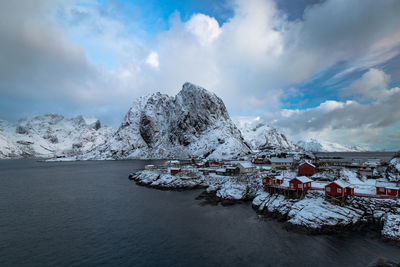 Scenic view of snowcapped mountains by sea against cloudy sky