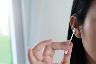 Woman cleaning ear with cotton swab. healthcare and ear cleaning