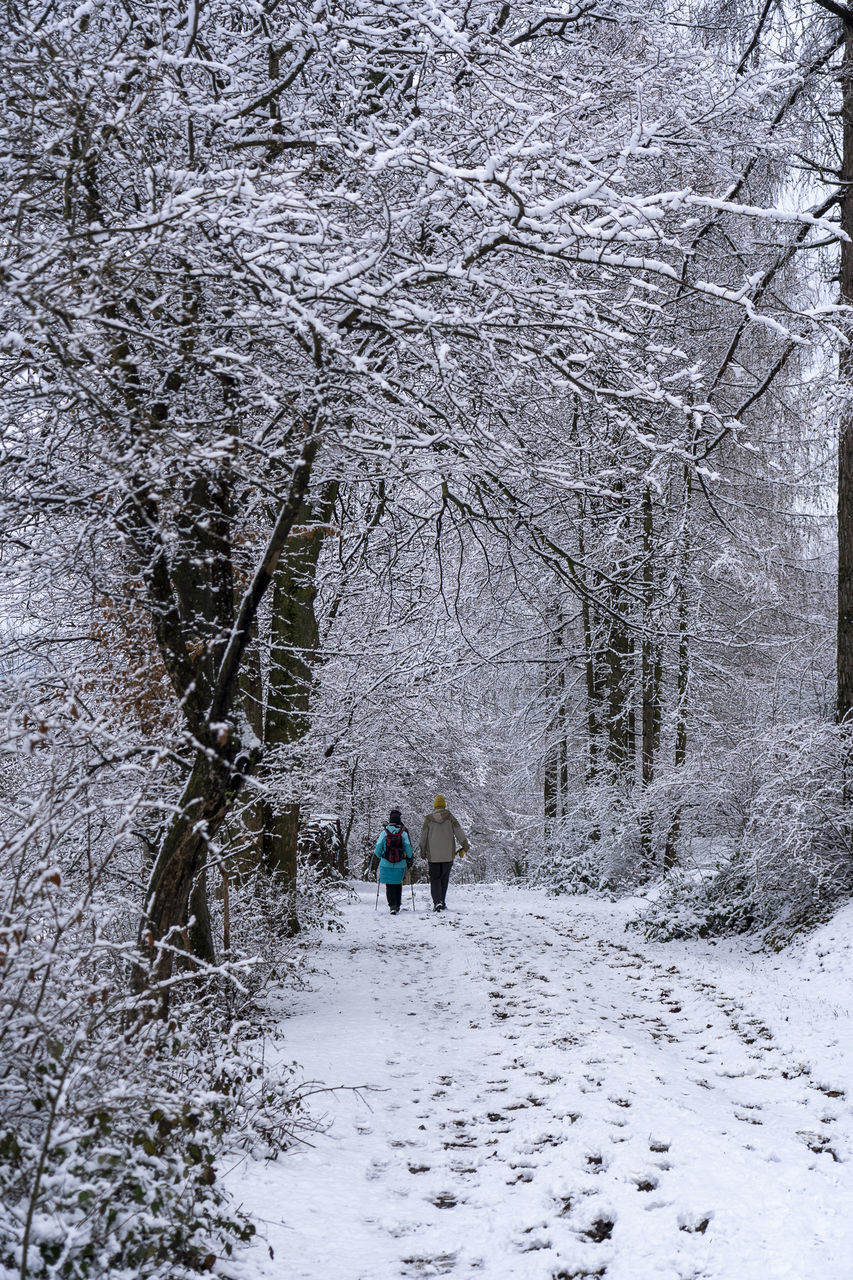 REAR VIEW OF PEOPLE ON SNOW COVERED LAND