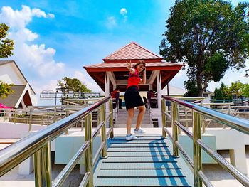 Side view of woman gesturing peace sign while walking on footbridge