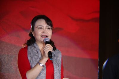 Woman speaking in microphone while standing on stage