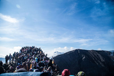 People on mountain against blue sky during sunny day