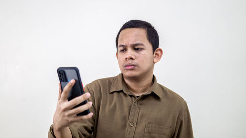 Portrait of man using smart phone against white background