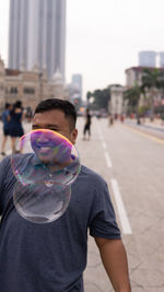 Midsection of man with bubbles in city