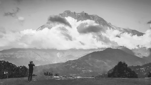 Rear view of man standing on mountain against sky