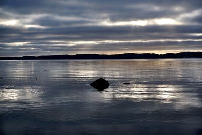 Scenic view of calm lake against cloudy sky
