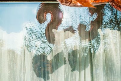 Close-up of woman standing by swimming pool against window