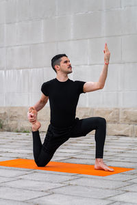 Handsome sporty latin man exercising in a city, doing yoga, fitness or pilates training