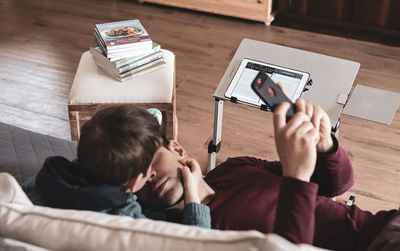 Rear view of man photographing with mobile phone at home