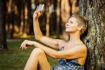 Woman taking selfie while sitting in forest