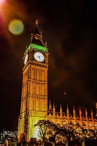 Low angle view of clock tower at night