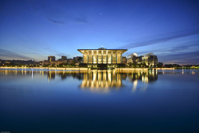 Tuanku mizan zainal abidin mosque by lake against sky at dusk