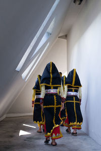 Rear view of women in traditional clothing standing in building 