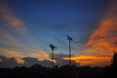 Low angle view of silhouette trees against dramatic sky during sunset