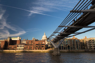 Bridge over river in city against sky