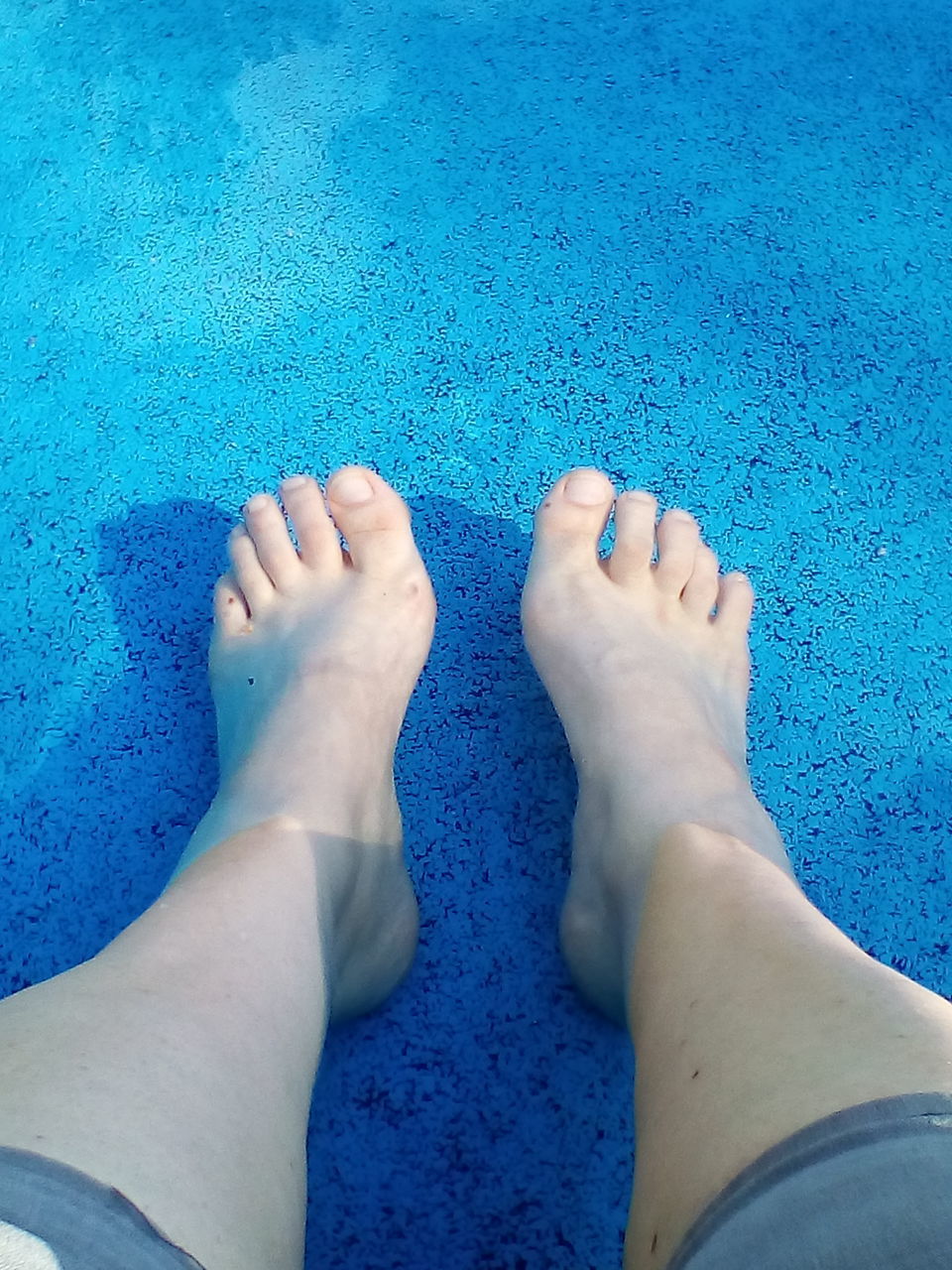 LOW SECTION OF WOMAN FEET IN BLUE WATER