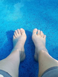 Low section of woman legs against blue water