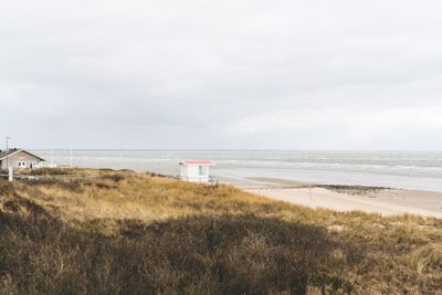 Beach hut by sea against sky