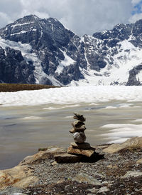 Stack of rocks on snow covered mountain against sky