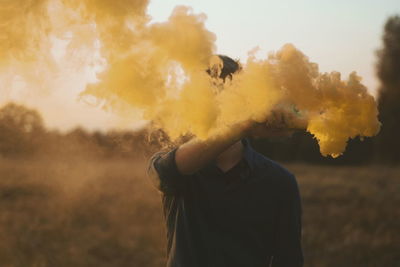 Yellow smoke emitting from distress flare being held by young man