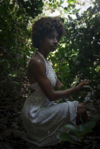 Portrait of young woman sitting on tree